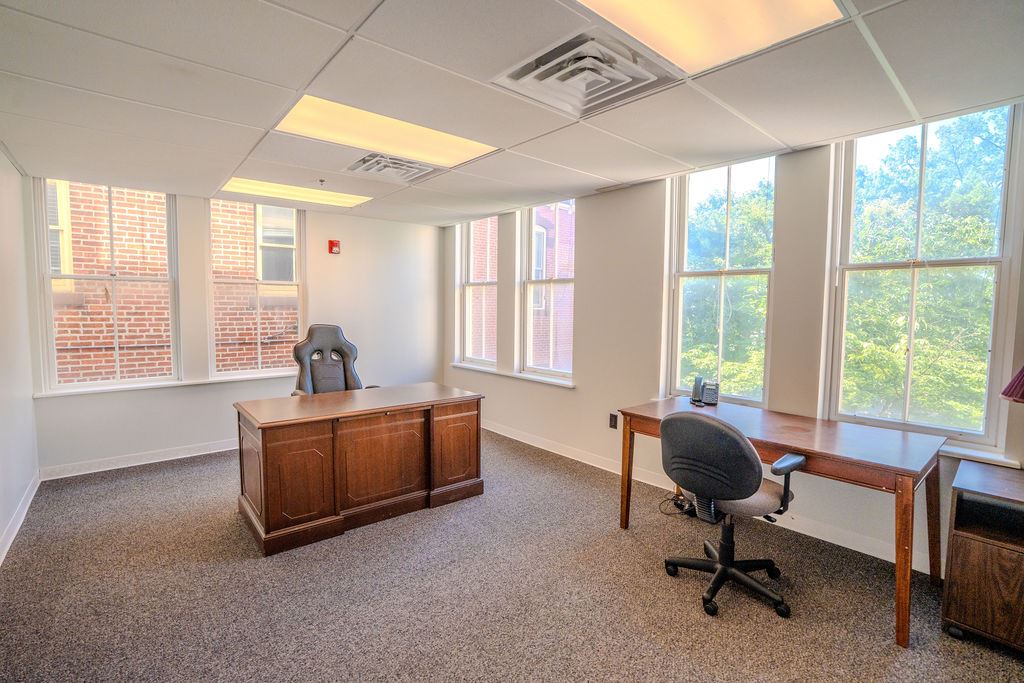 Room with many big windows, two desks, and chairs